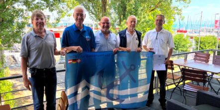 Fünf Männer stehen nebeneinander und halten eine blaue Fahne.