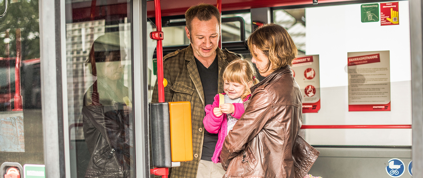Eltern mit einem Kleinkind im Bus beim Ticketlösen