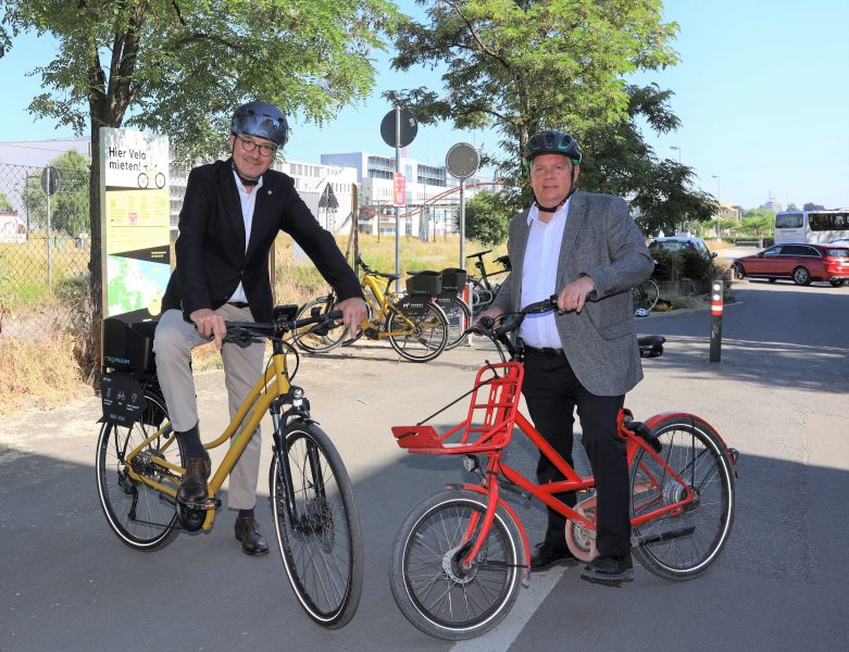Zwei Männer mit Helmen sitzen auf zwei Fahrrädern.